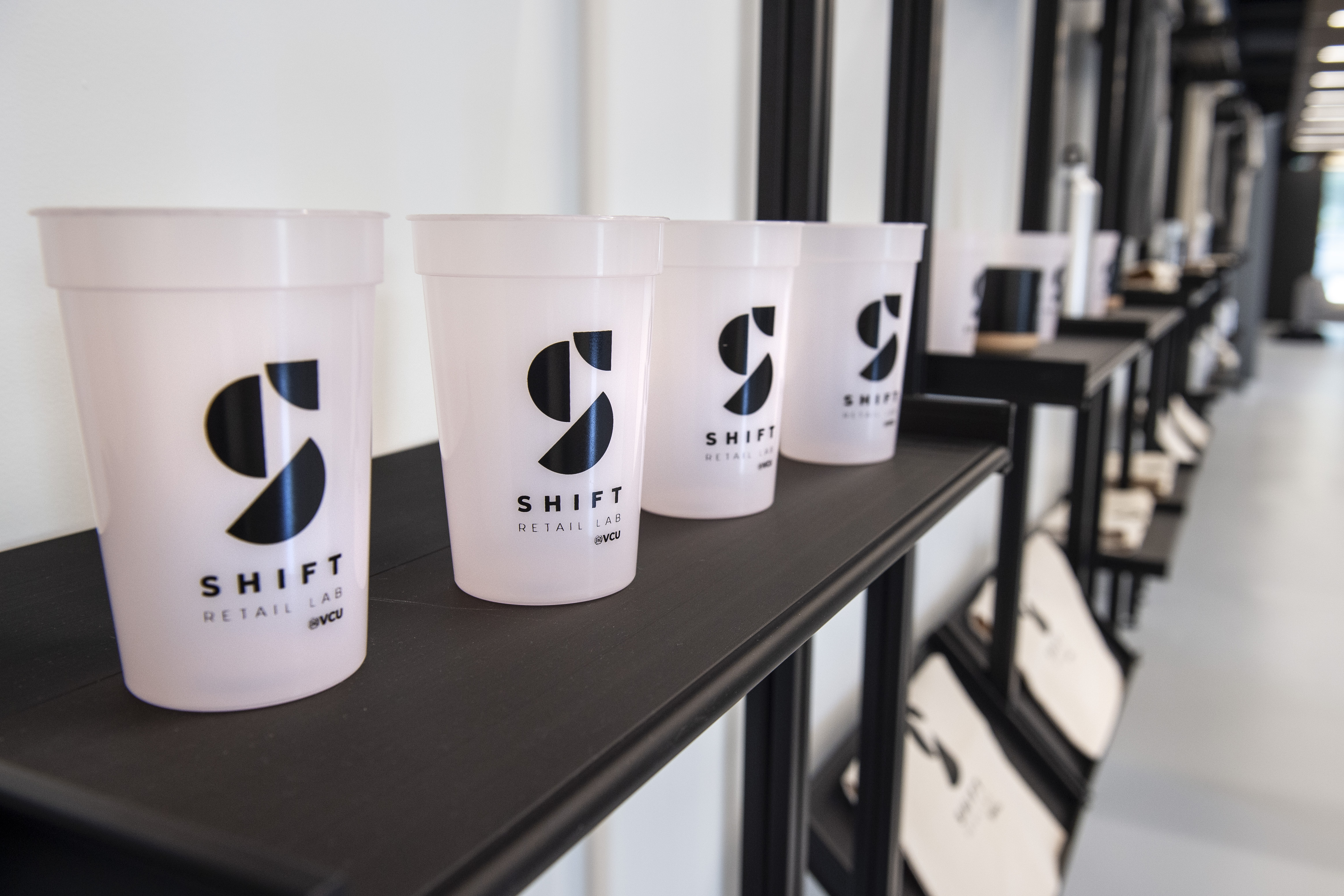 translucent pink cups with the shift retail lab logo arranged in a line across a row of shelves