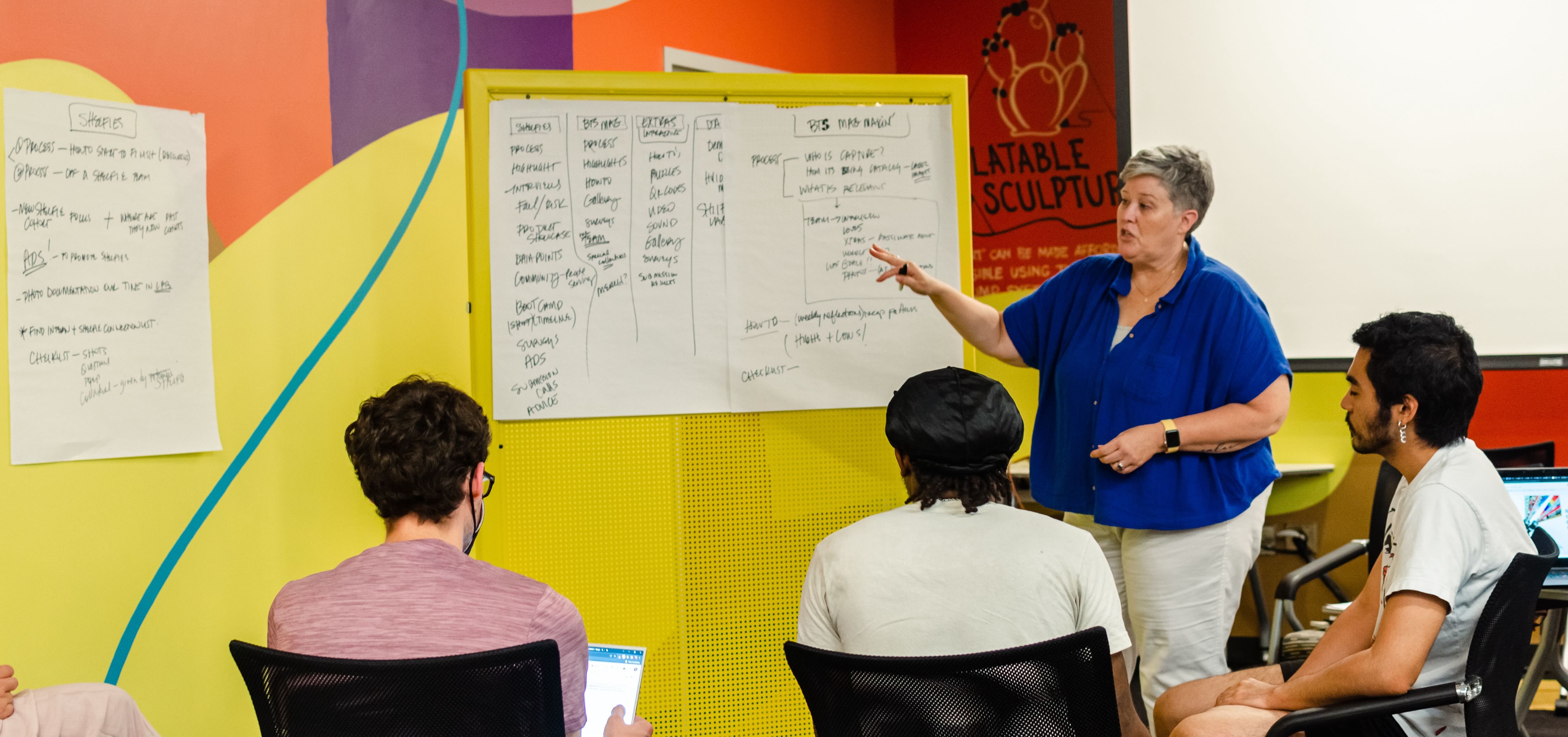 woman leading a small group discussion in front of a white board