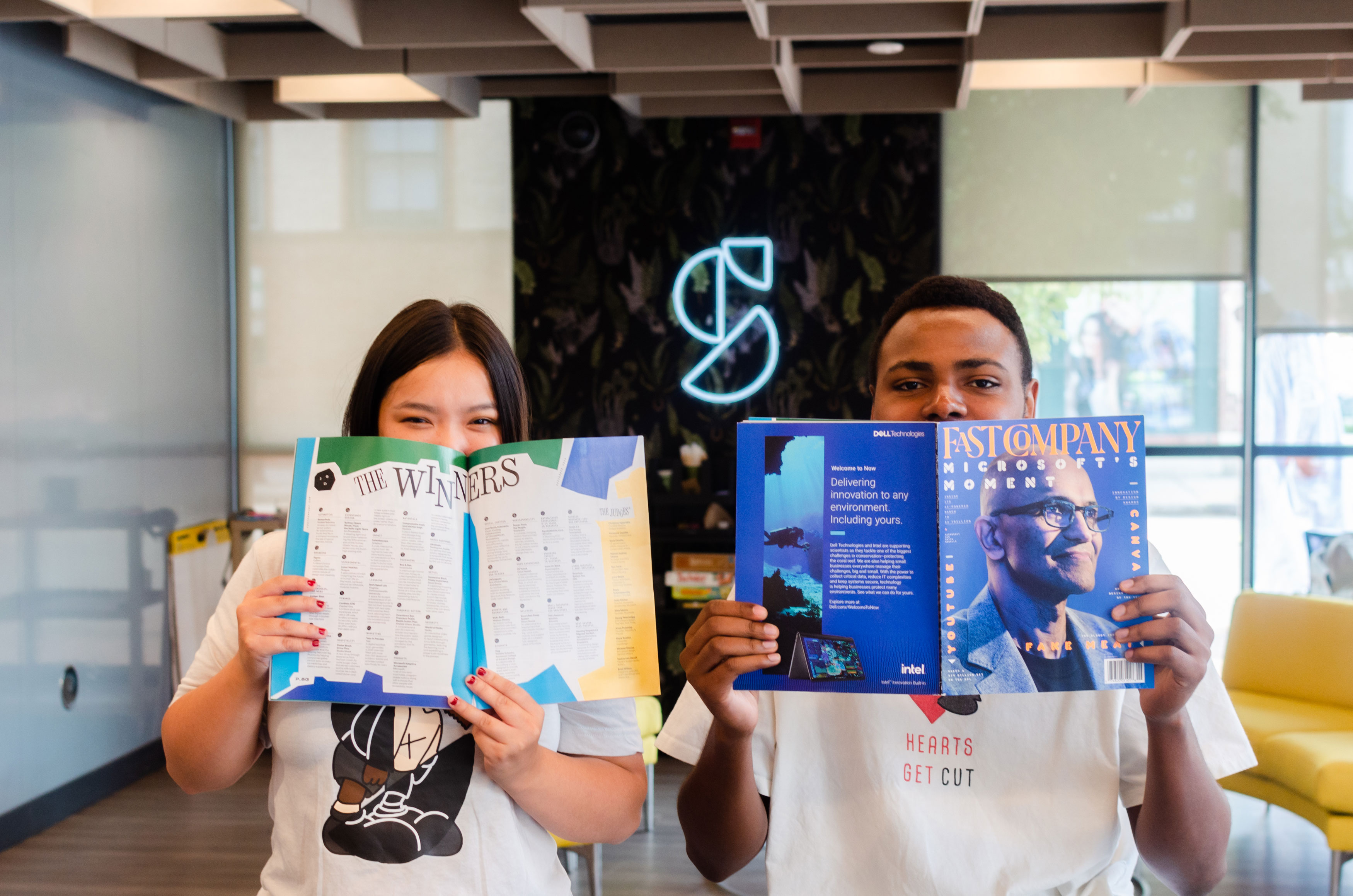 two students holding up the Fast Company Magazine